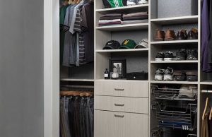 Off-white reach-in closet organizer system filled with shoes and clothes