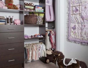Dark wood organizer system in kids' closet with clothes and toys