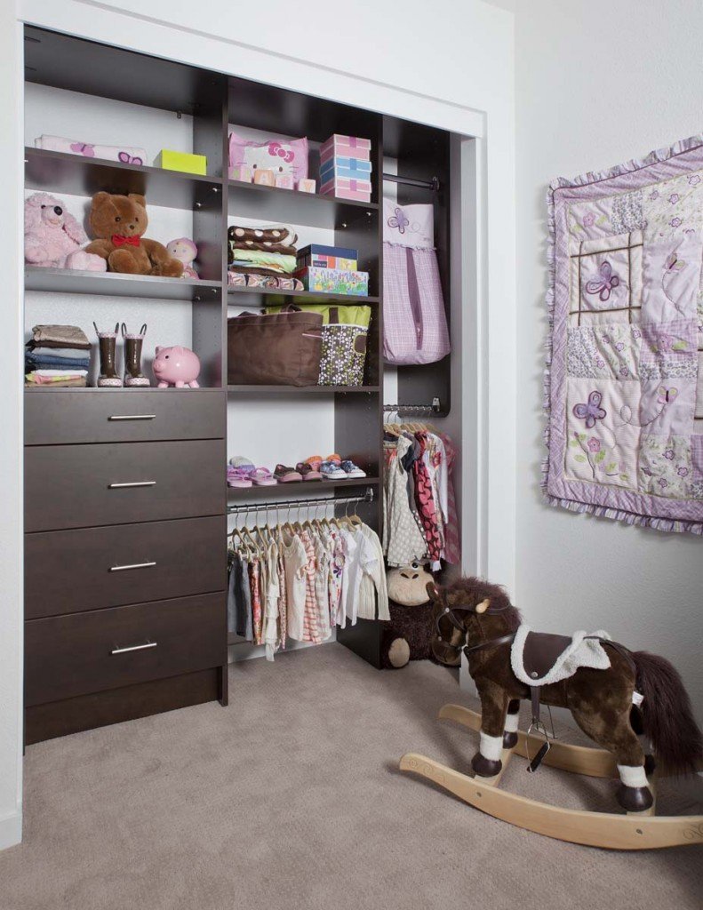 Dark wooden kids' closet organization system stocked with clothes, shoes, toys, and accessories