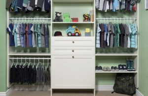 White closet organizer system with kids' clothes, shoes, and toys in green room