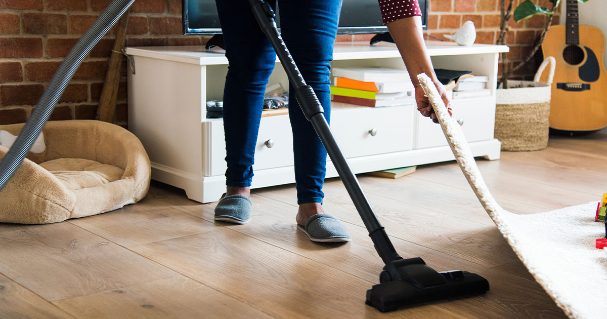 a homeowner vacuuming beneath carpet