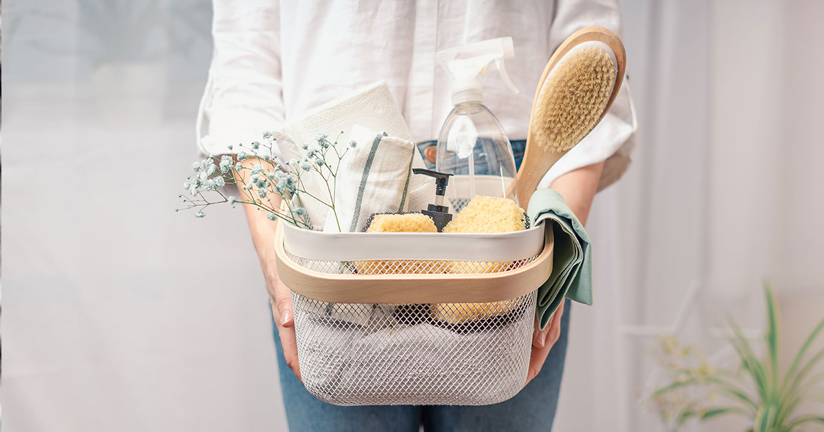 A woman holding a basket filled with cleaning products
