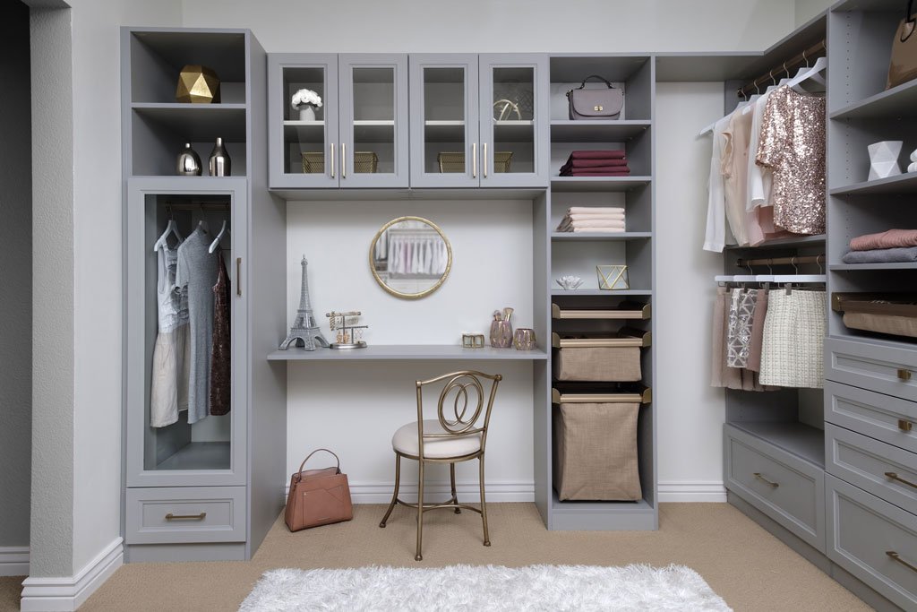 Side view of walk-in closet organization system and vanity area stocked with clothes, shoes, and accessories