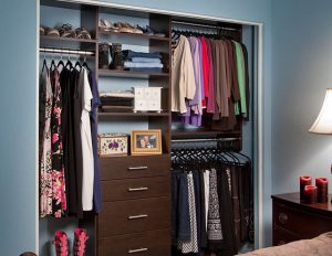 Dark wood reach-in closet organizer system in blue bedroom