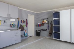 Garage with custom wall storage system and light colored cabinets