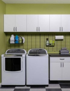 Cabinets and wall storage in yellow laundry room with white appliances