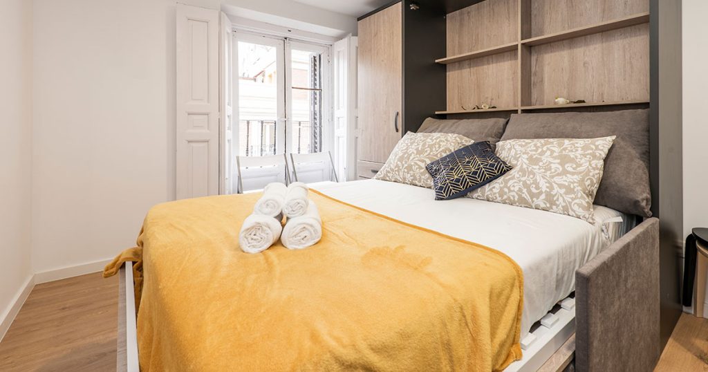 A Murphy bed with yellow bed sheet