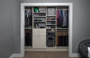 Off-white reach-in closet organizer system with clothes, shoes, and a storage basket