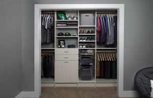 Off-white reach-in closet organizer system with clothes and shoes
