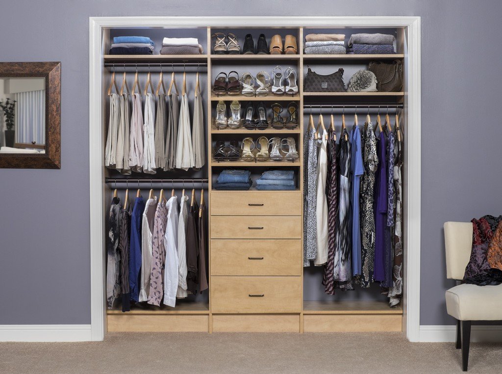 Natural wood reach-in closet organization system stocked with clothes, shoes, and accessories