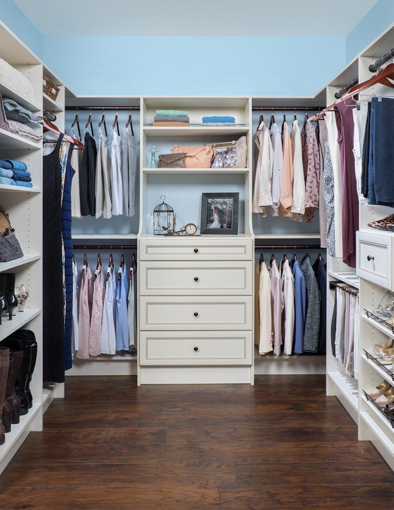 Front view of beige walk-in closet organization system stocked with clothes, shoes, and accessories