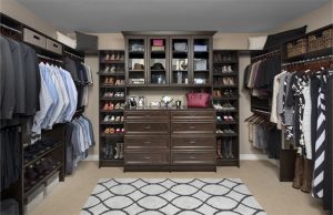 Dark wood closet organizer system with men's and women's clothes and shoes