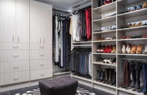 Gray wood closet organizer system with clothes, shoes, and boots