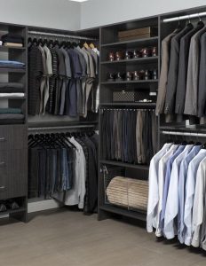 Dark wooden closet organization system with clothes hanging on racks
