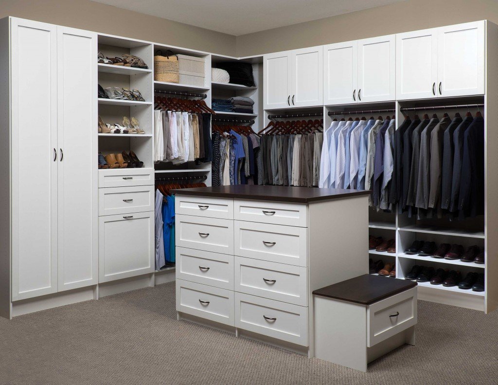 Front view of walk-in closet organization system and center island stocked with clothes, shoes, and accessories