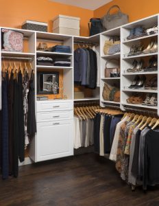 Custom closet system with shelving, cabinets, and racks in an orange walk-in closet