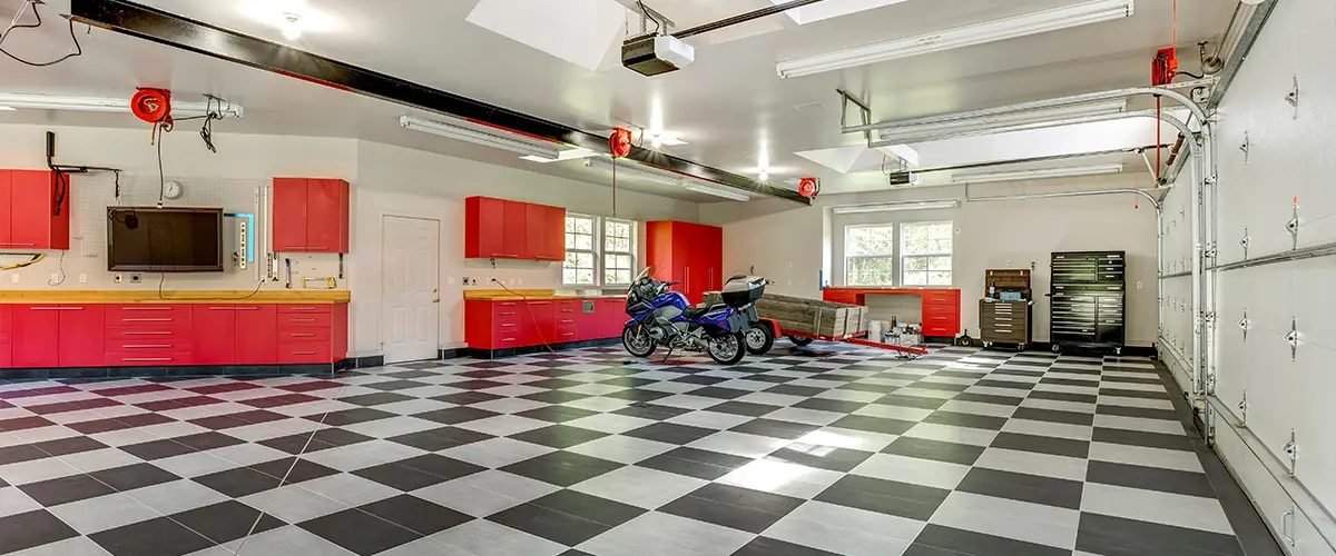 Large garage with black and white tile floor and red garage cabinets