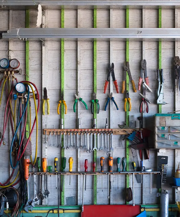 Old hand tools hanging on wall in workshop or auto service garage, many tool shelf against a wall, car mechanic concept.