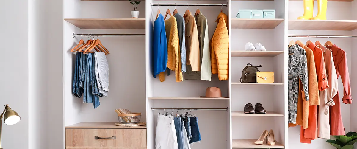 Organized closet with clothes on hangers, shelves, and drawers
