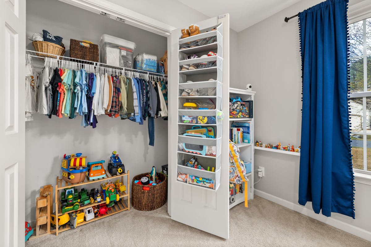 Organized children's closet with custom shelving, colorful clothes, and toys neatly arranged